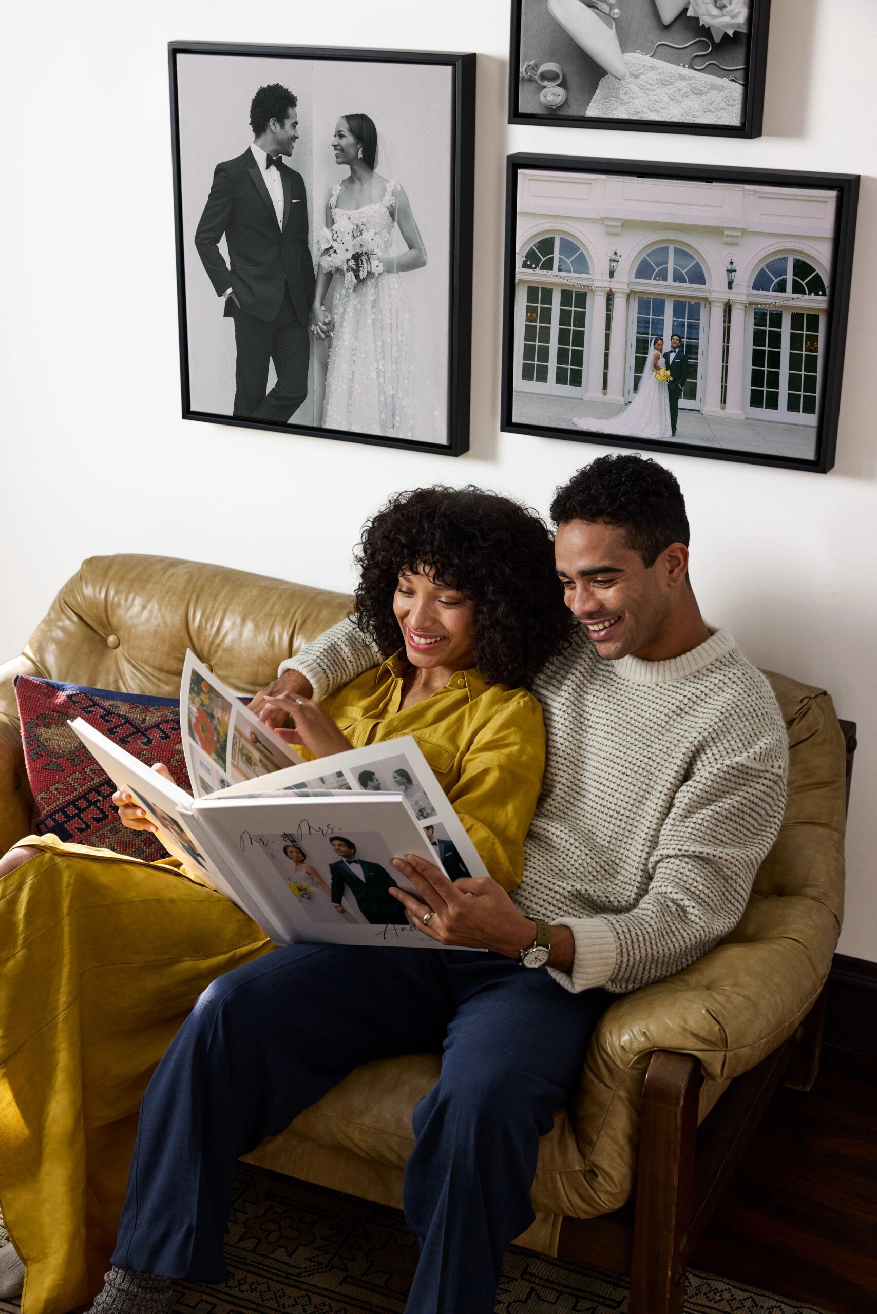 16x20 and 20x24 canvas print with wedding photos above couple on couch looking at photo book